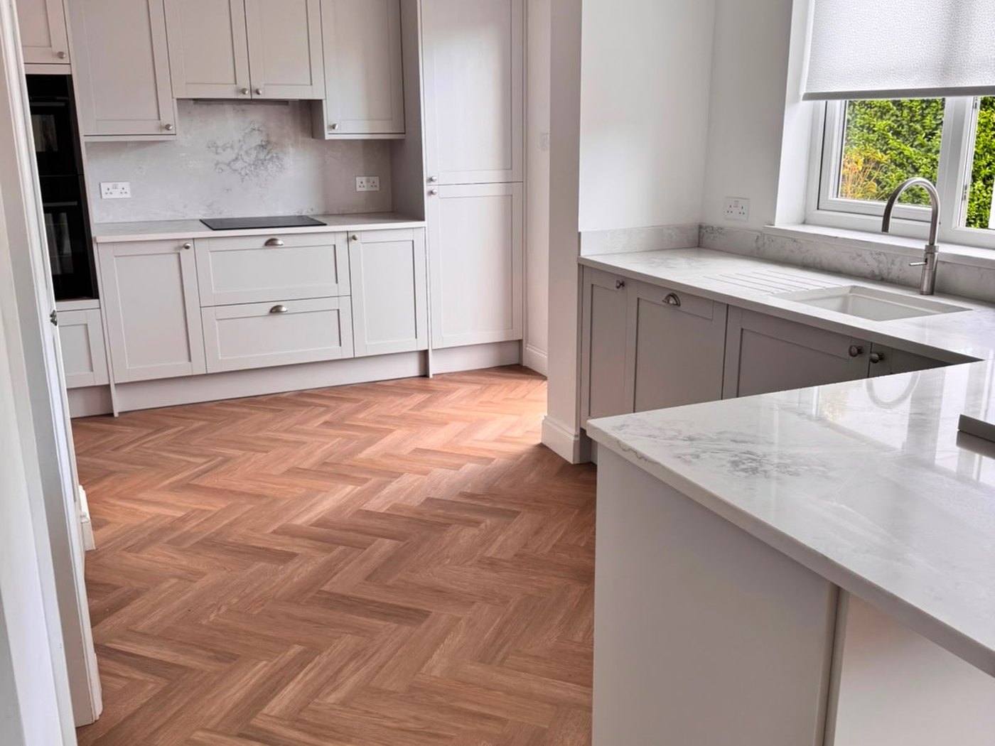 The same kitchen refitted in pale shaker units with a marble worktop
