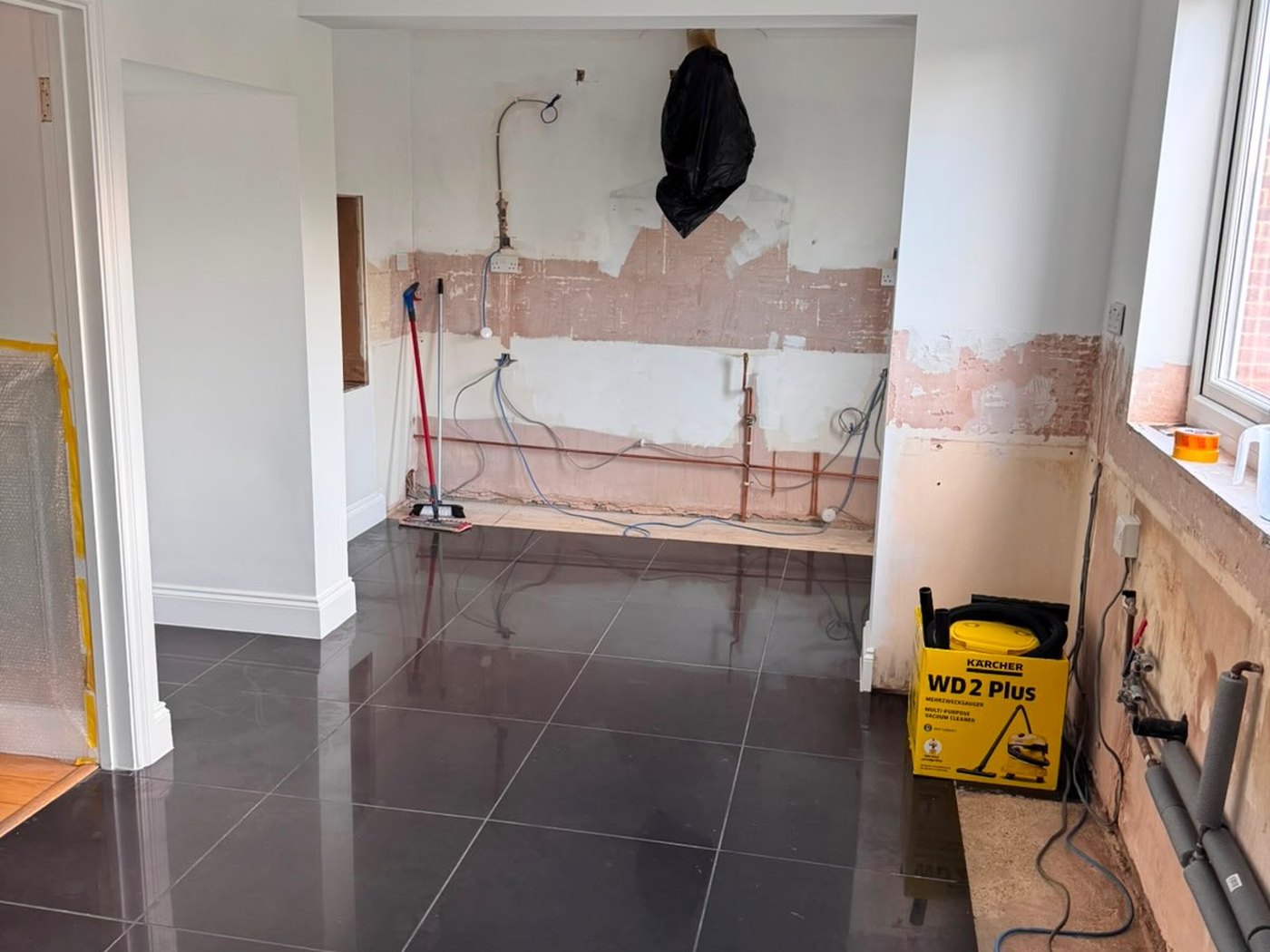Kitchen stripped back to bare plaster with the old pipework exposed