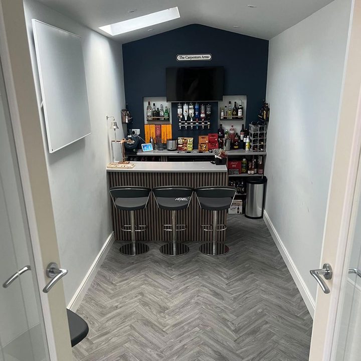 Built in home bar with stools over a herringbone floor