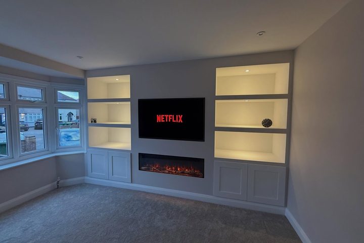 Media wall with lit shelving either side of an inset fire