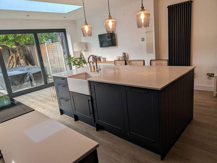 Dark kitchen island with copper pendants and bifold doors behind
